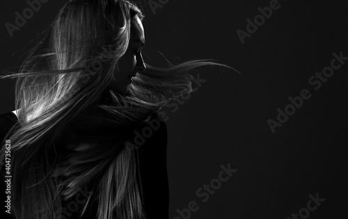 Black and white portrait of pretty woman fairy with beautiful long flying hair after hair restoring spa procedures standing with her head turned looking aside at copy space . Hairstyle. Hair cosmetics photo