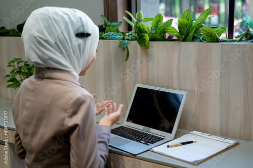 Smiling Indian female employee with headset working and talk on video call,have web conference with colleagues. photo