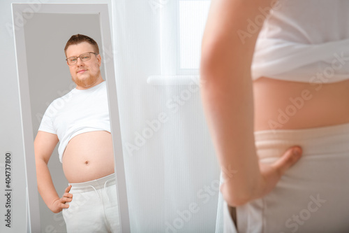 Overweight man near mirror ...
