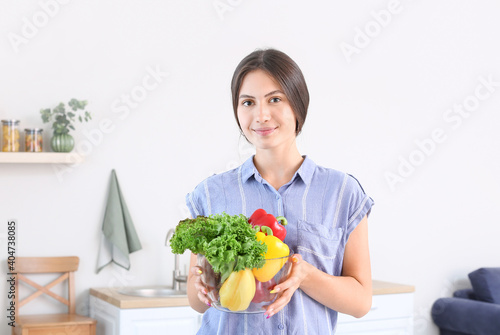 Beautiful young woman with vegetables in kitchen