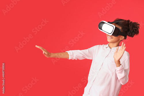 Teenage African-American girl with virtual reality glasses on color background