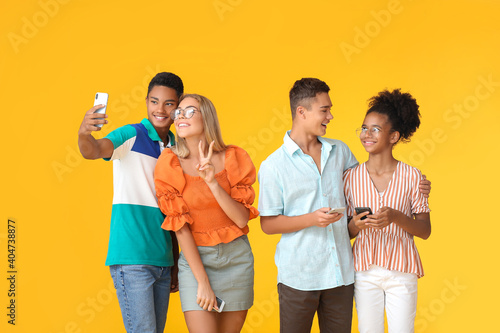 Teenagers with modern mobile phones on color background