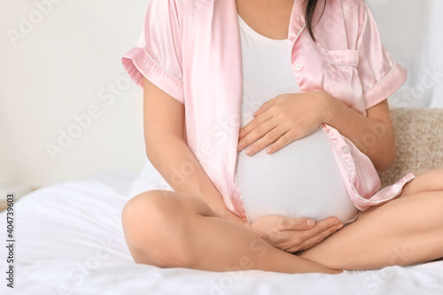 Pregnant young woman in bedroom