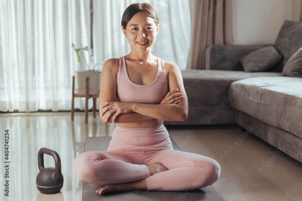Young woman in sportwear sitting on yoga mat at home. fit asian woman doing exercise at home. Home exercise. Young woman in sportwear sitting on yoga mat at home. fit asian woman doing exercise at home. Home exercise.