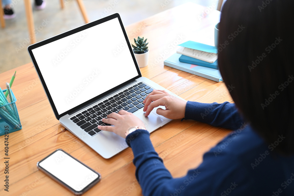 Rear view of female freelance working with laptop computer on wooden table. Rear view of female freelance working with laptop computer on wooden table.
