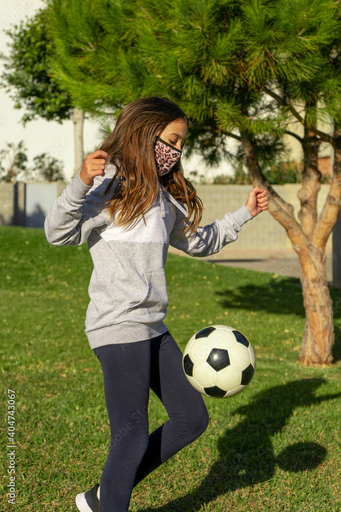 Beautiful little girl playing soccer in a nice park with natural grass on a sunny winter day. Copy space Beautiful little girl playing soccer in a nice park with natural grass on a sunny winter day. Copy space