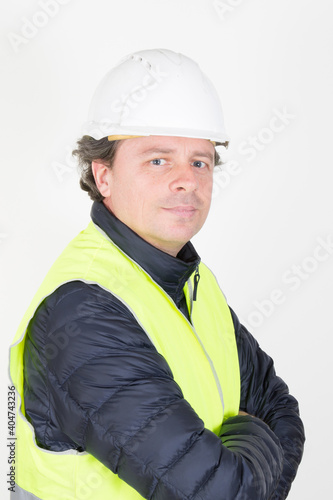 handsome workman with helmet arms crossed yellow vest in white background