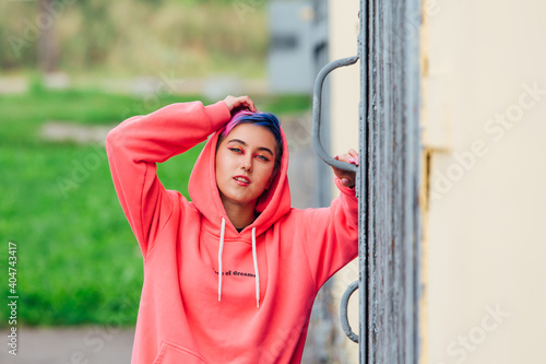 Portrait of a young girl with short colorful hair and nose piercing satanding near the wall with wooden door. photo