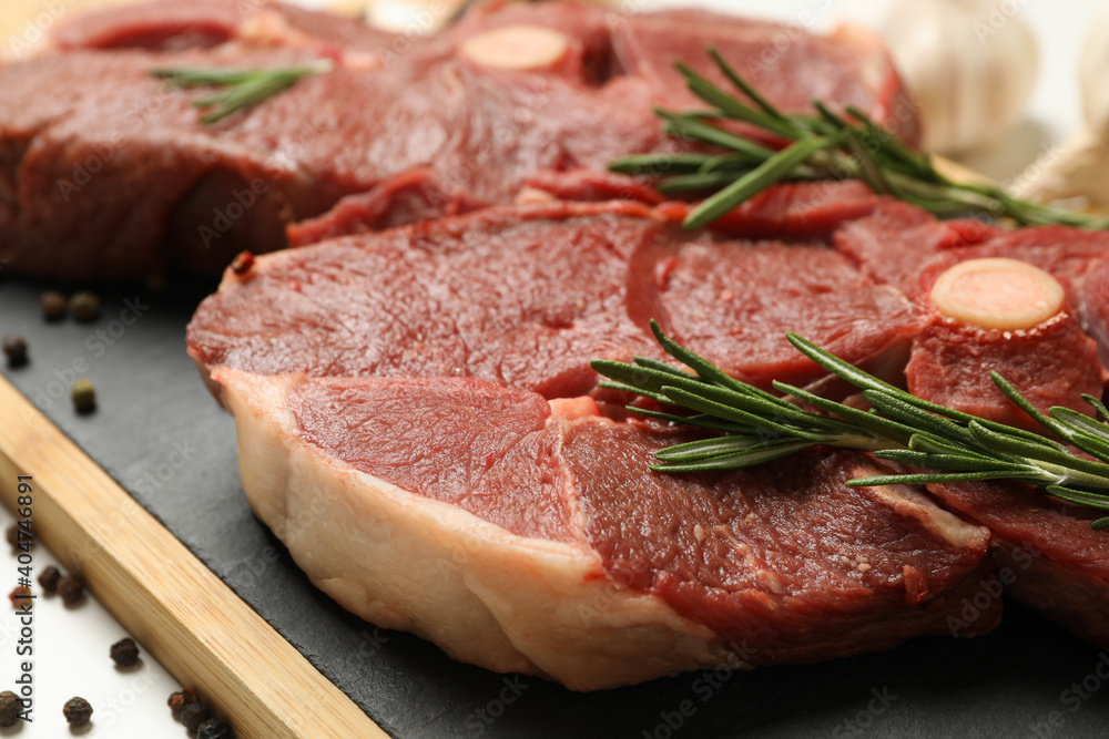 Board with fresh raw steak meat with rosemary, close up