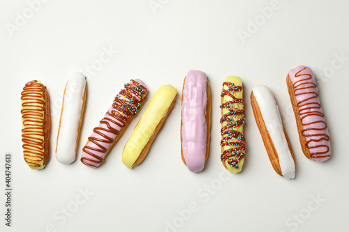 Tasty eclairs with different topping on white background