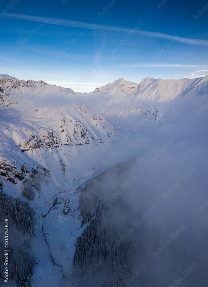 Obraz premium Aerial drone view of the amazing curved windy road motorway Transfagarasan in Romania during a winter morning landscape with mountains in background
