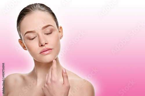 Portrait of natural young girl without makeup touching her face on a pink background with a shaded white outline