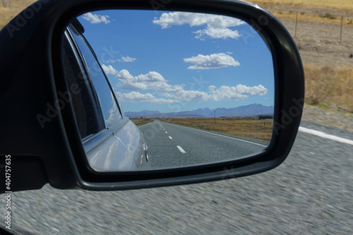 Road and rural scenery behind in rearvision mirror