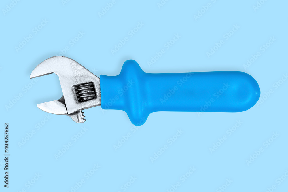Adjustable metal wrench with a rubberized handle on a blue background. Adjustable metal wrench with a rubberized handle on a blue background.