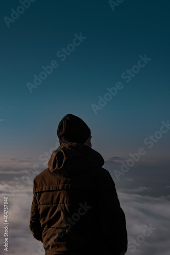 Man in a jacket in the mountains. The guy dreams and looks into the distance.