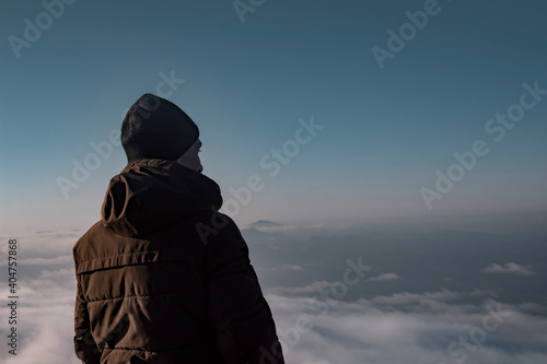 Man in a jacket in the mountains. The guy dreams and looks into the distance.