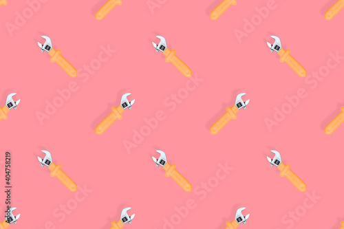 Adjustable metal wrench seamless pattern. Adjustable metal wrench on a red background.