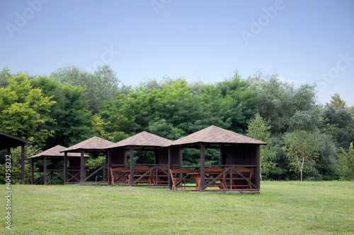 Old wooden bench and a table made of solid round timber in a gazebo, outdoor recreation