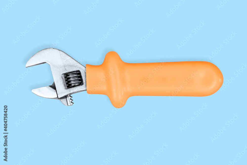 Adjustable metal wrench with a rubberized handle on a blue background. Adjustable metal wrench with a rubberized handle on a blue background.