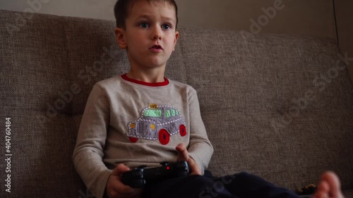 Little boy playing video game seated on a sofa