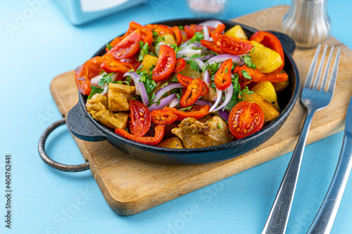 Tomatoes, red peppers, onions, potatoes and meat in a frying pan. Vegetable stew. Pork ojakhuri with vegetables. Georgian cuisine. Home menu.  photo