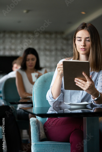 Happy woman manager holding tablet and sitting in cafe