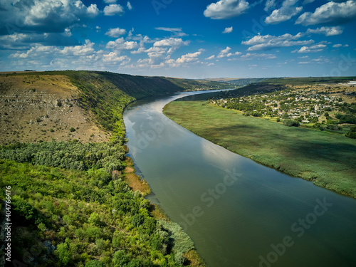 Flight through majestic river Dnister, lush green forest and village. Moldova, Europe. Landscape photography.