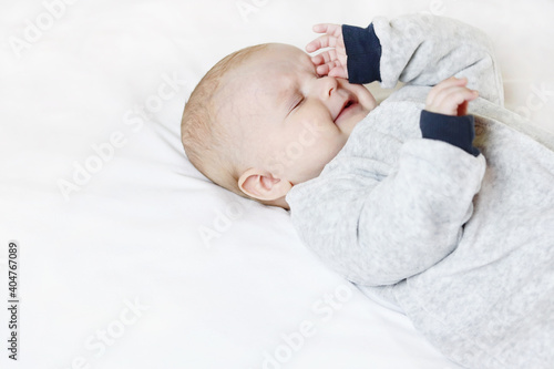 A crying, sad child rubs his eyes and puffs out his face, feeling sleepy. Copy space - concept of loneliness, needs attention, baby care, baby sleep, whims