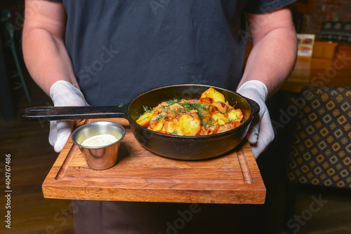Fried potatoes in an iron pan served in a restaurant or diner. Waiter service, eating out concept.