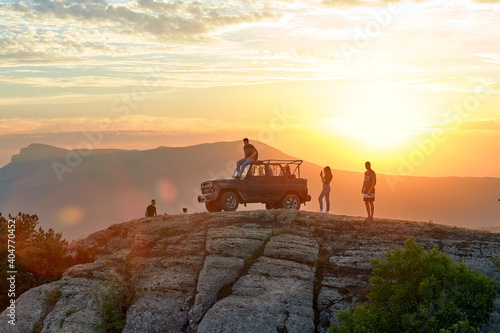 tourists arrived by jeep on a high mountain against the background of sunset and mountains