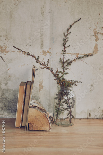 still life in the form of a glass transparent vase with dried grass and books on the background of a vintage wall (ID: 404771454)