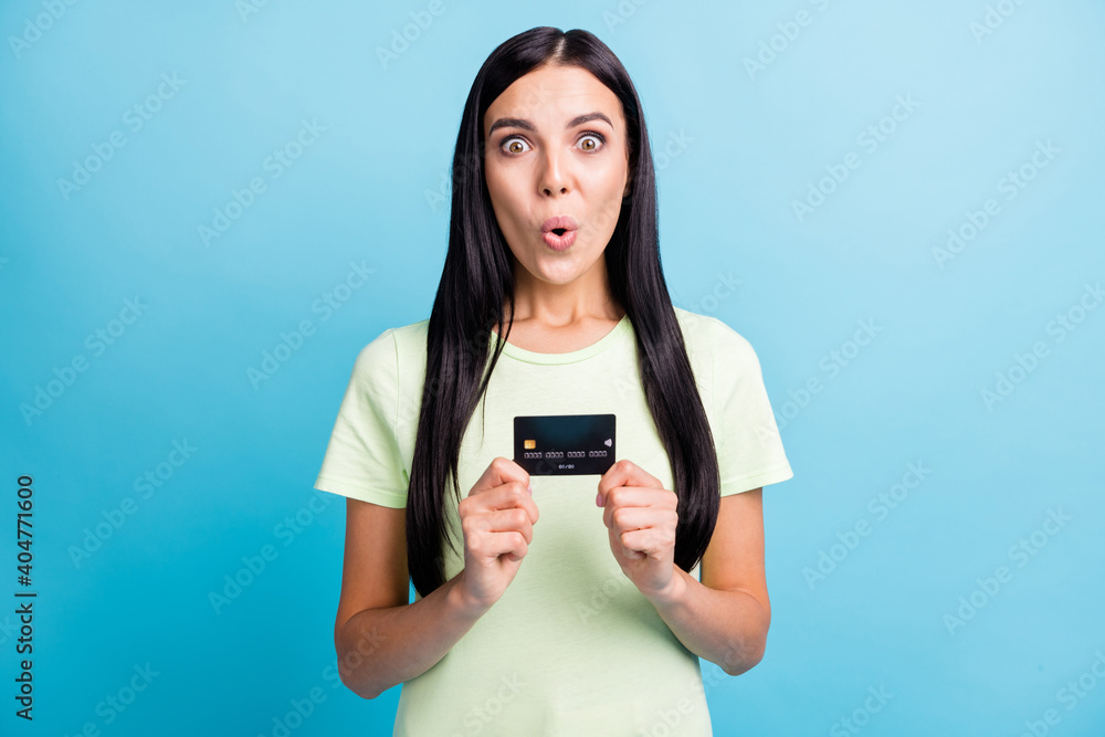 Photo portrait of impressed woman holding credit card in two hands isolated on pastel blue colored background Photo portrait of impressed woman holding credit card in two hands isolated on pastel blue colored background