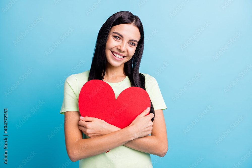 Photo portrait of woman hugging big red heart paper cutout isolated on pastel blue colored background Photo portrait of woman hugging big red heart paper cutout isolated on pastel blue colored background