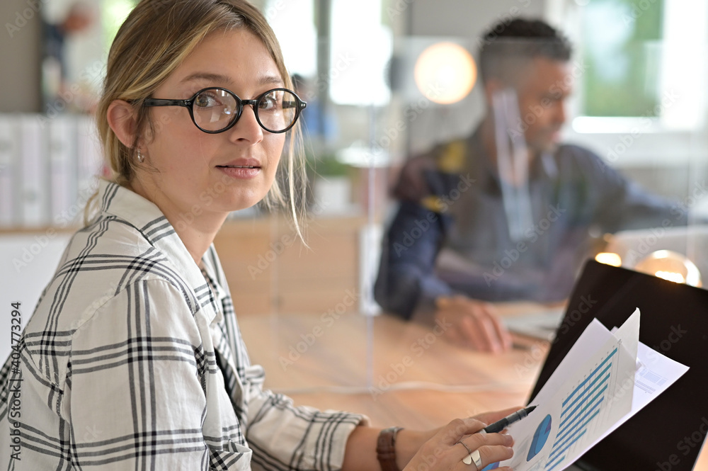 Office worker with eyeglasses working in open space area protected with plexiglas Office worker with eyeglasses working in open space area protected with plexiglas