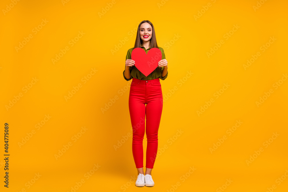 Full length body size view of nice cheerful straight-haired girl holding in hands heart isolated on bright yellow color background