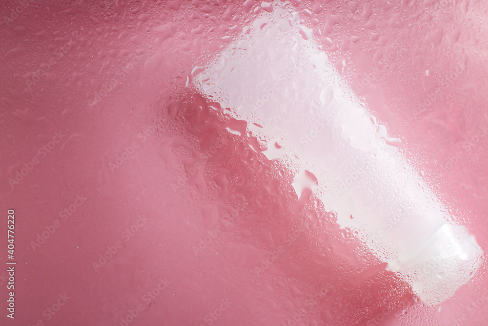 Fototapeta premium moisturizing skin care products. Face and hand cream under a glass surface with water on a pink background. spa cosmetic