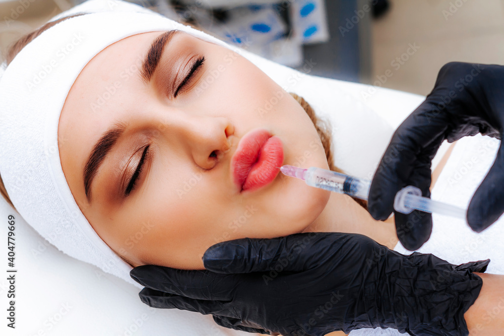 Lip augmentation procedure with hyaluronic acid. The beautician pierces the lips with a needle. Subcutaneous injection.