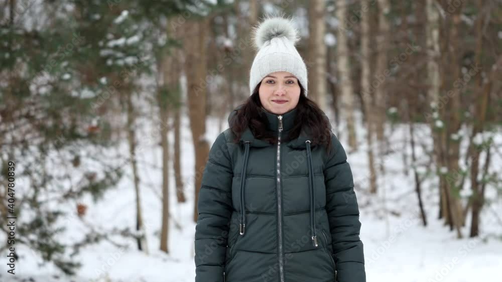 Portrait of young beautiful woman in winter clothes standing on background of the forest in winter weather and smiles at camera. Portrait of young beautiful woman in winter clothes standing on background of the forest in winter weather and smiles at camera.
