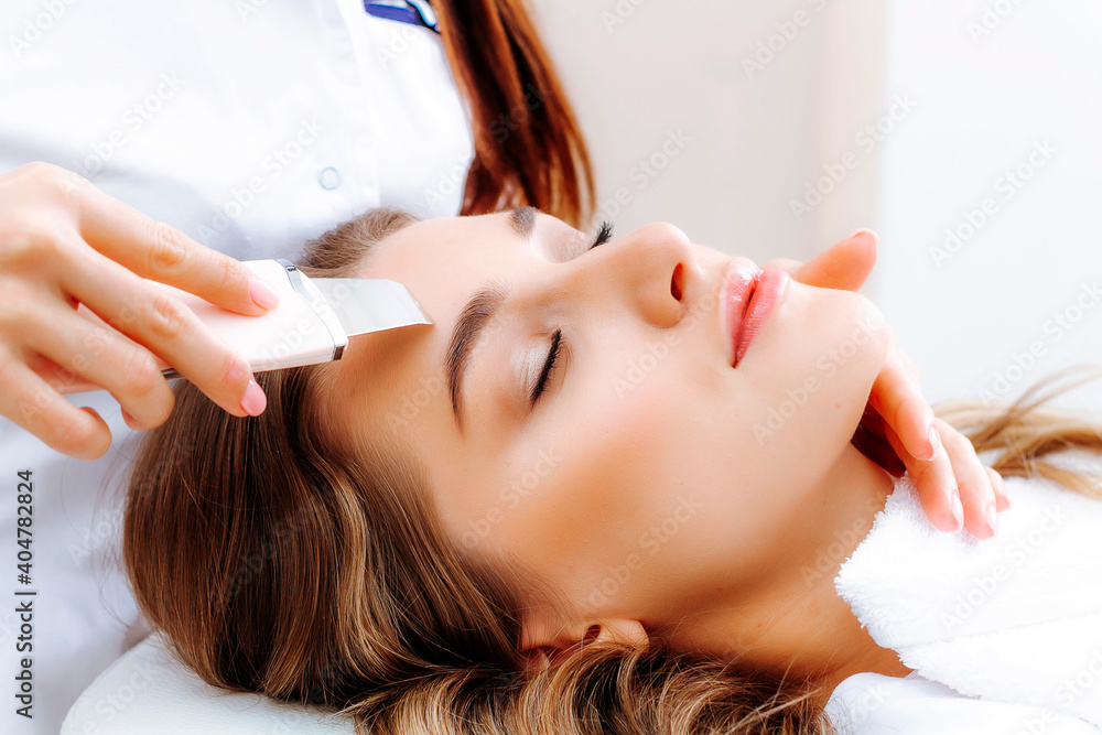 Naklejka premium Ultrasonic facial cleansing procedure by a beautician. Skin cleansing. Problem skin treatment.