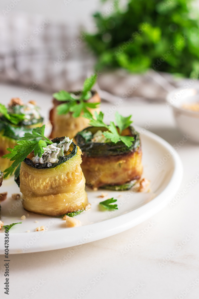 Roasted zucchini rolls stuffed with cheese on white plate