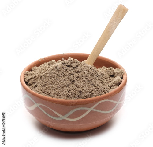 Linseed protein powder pile in clay bowl with wooden spoon, organic supplement isolated on white background