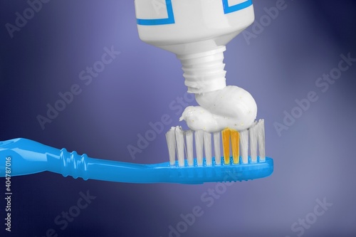 White toothpaste on a toothbrush on colored background