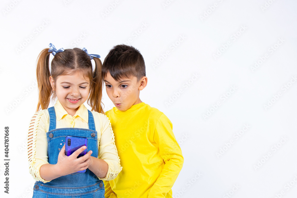 Preschool children are watching something on a smartphone. A boy with a surprised face. White background and side space. Preschool children are watching something on a smartphone. A boy with a surprised face. White background and side space.
