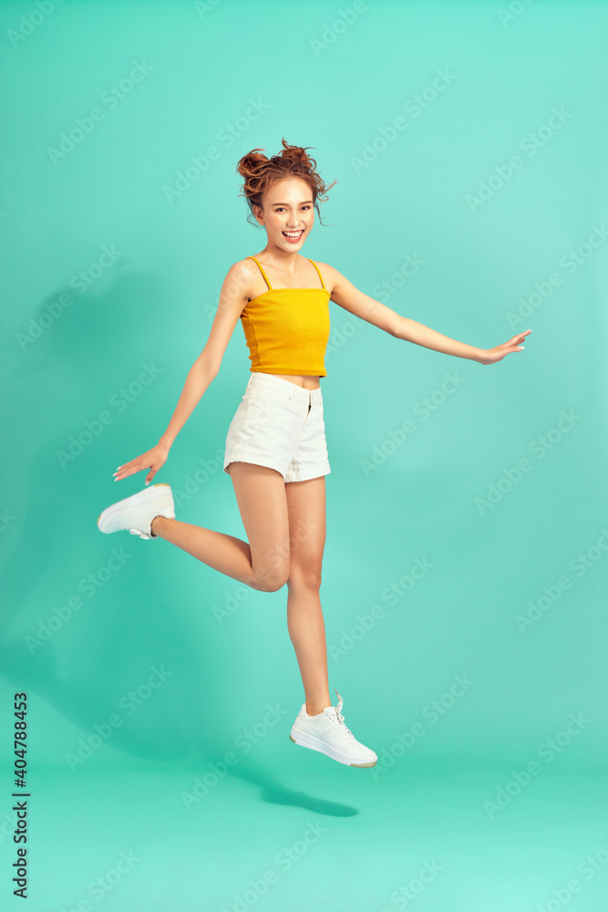 Full length of Cheerful young Asian woman jumping over light green background. Full length of Cheerful young Asian woman jumping over light green background.