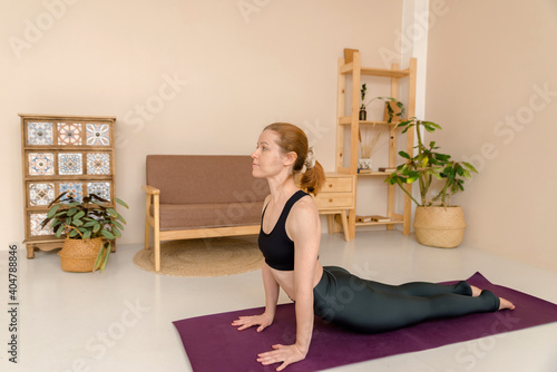Pleasant woman in sports clothing doing yoga while relaxing at home, health concept
