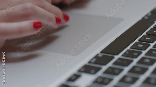 Une femme avec du vernis à ongle rouge utilise son ordinateur portable