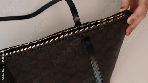 Closeup of Young womans hand opens her bag. Girl opens zip lock on bag