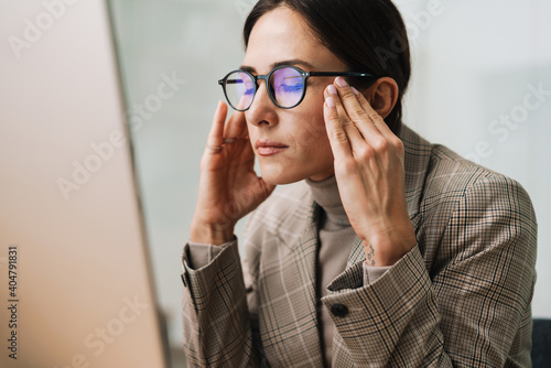 Tired charming woman with headache working with computer in office