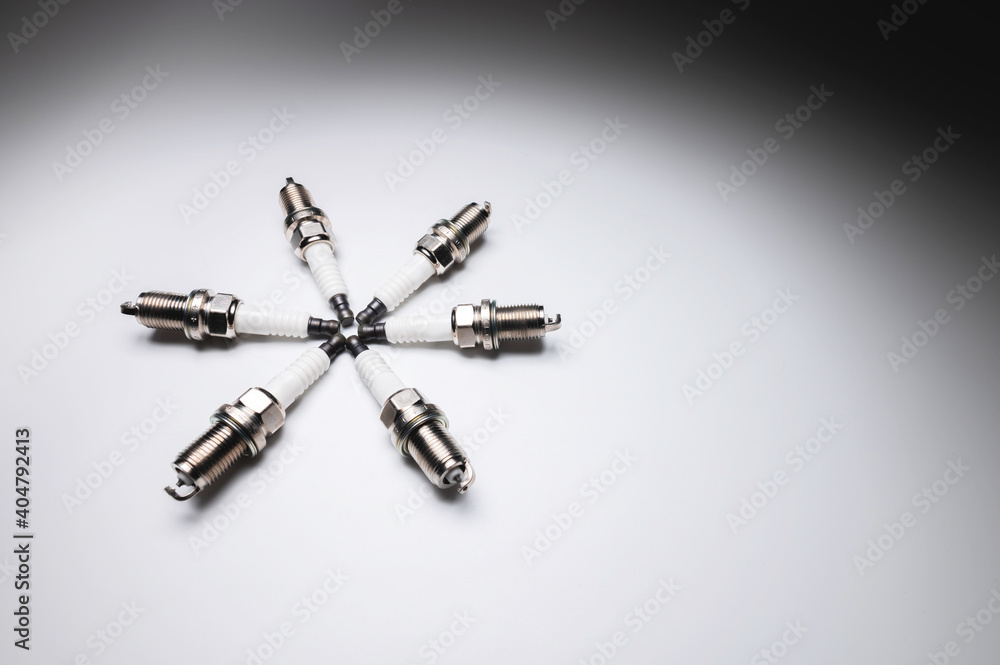 Six new ICE spark plugs on a gray background in contrasting light Six new ICE spark plugs on a gray background in contrasting light