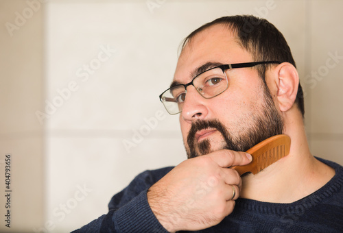 Adult man comb his beard and moustache